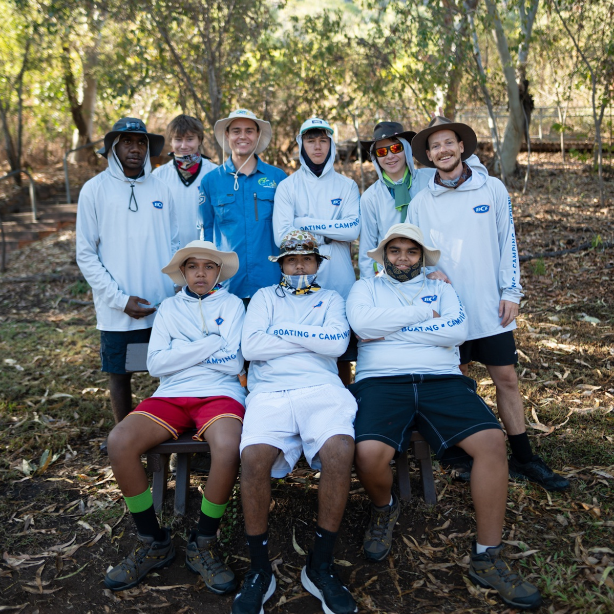 Group of young men and mentors pose together outdoors in bushland.